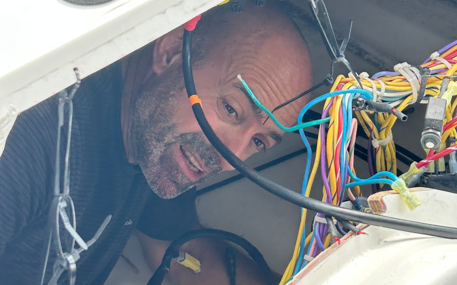 Technician tracing marine wiring inside an open helm