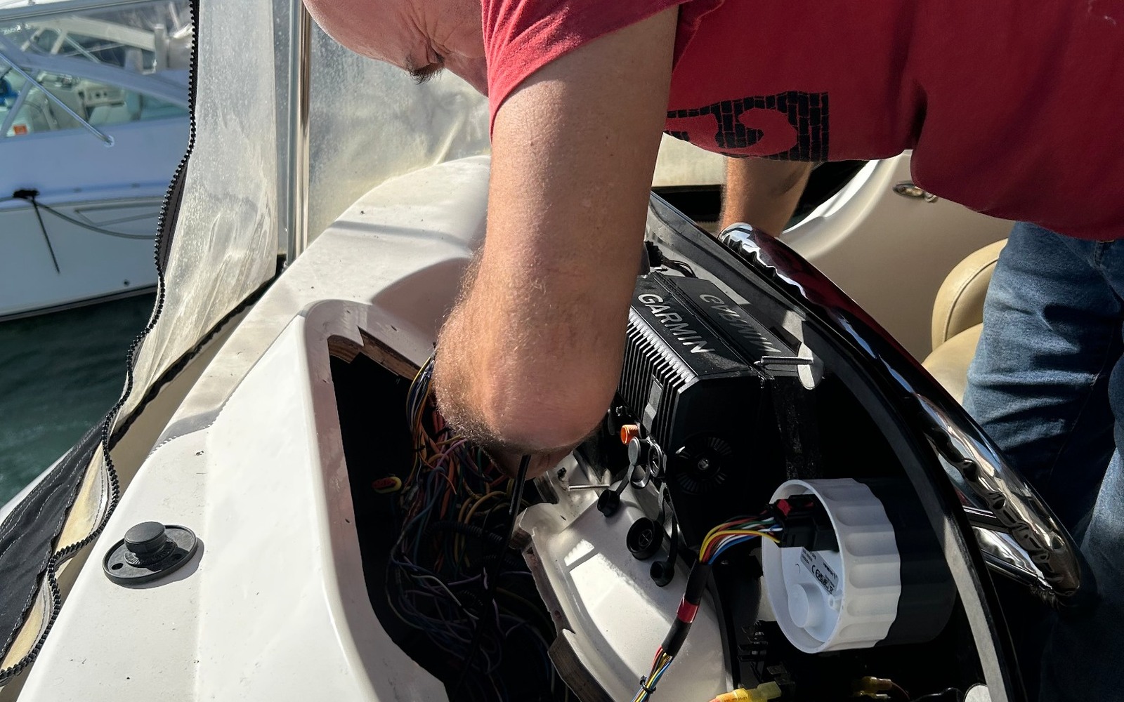 Technician working inside an open helm with exposed marine wiring